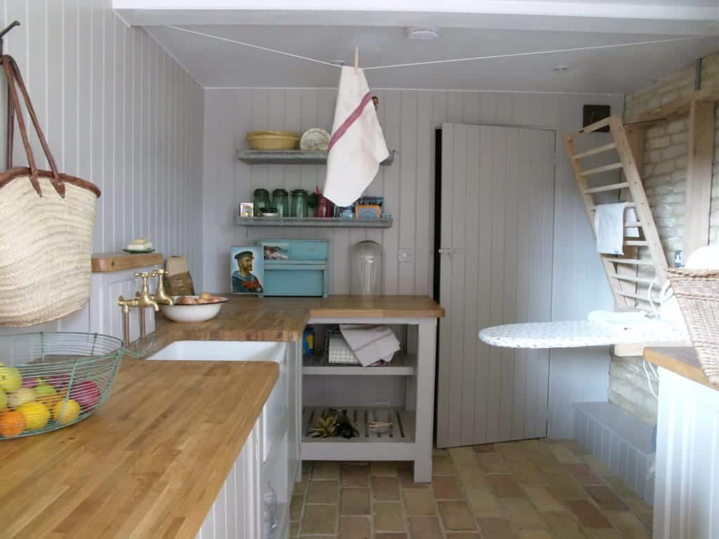 一间小洗衣房和厨房区，铺着陶土砖地板。