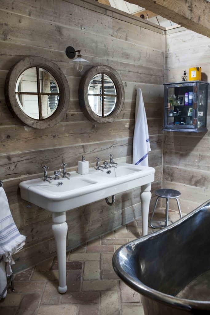 一个浴室和一个双水槽和独立式浴缸以及砖terracotta瓷砖地板。