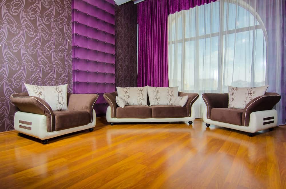 宽敞的客厅设有一套优雅的棕色座椅和紫色的口音。这些墙看起来很可爱。