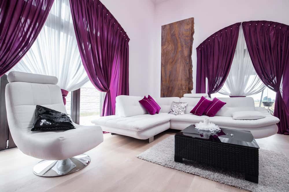 这个时尚的生活空间以白色和紫色为特色。它的紫色基调使这个房间看起来很精致。白色的沙发和时髦的椅子很有品位。