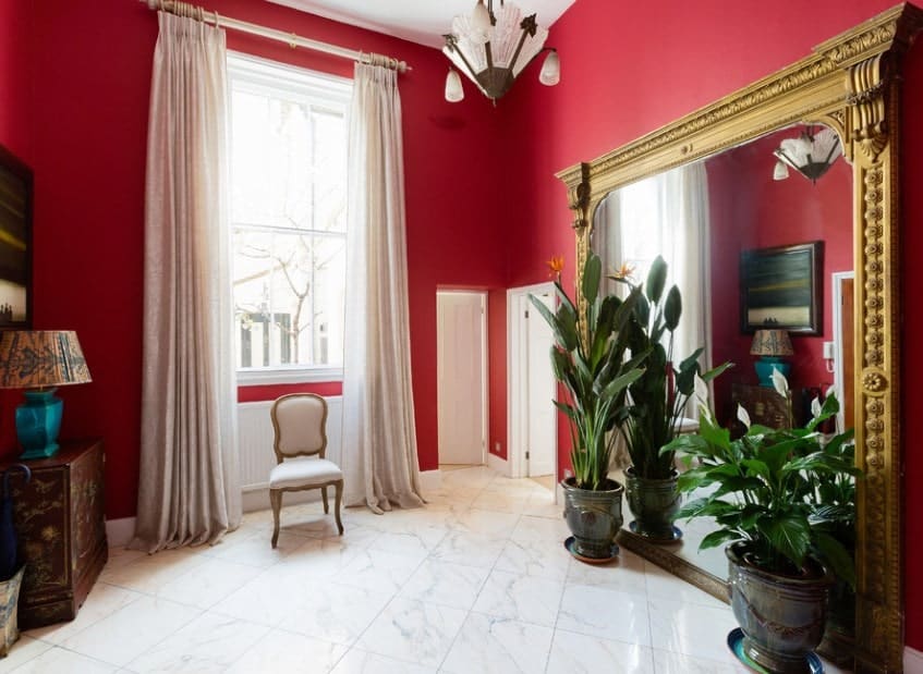 这个门厅以红色的墙壁和白色的瓷砖地板以及绿色的盆栽植物为特色。