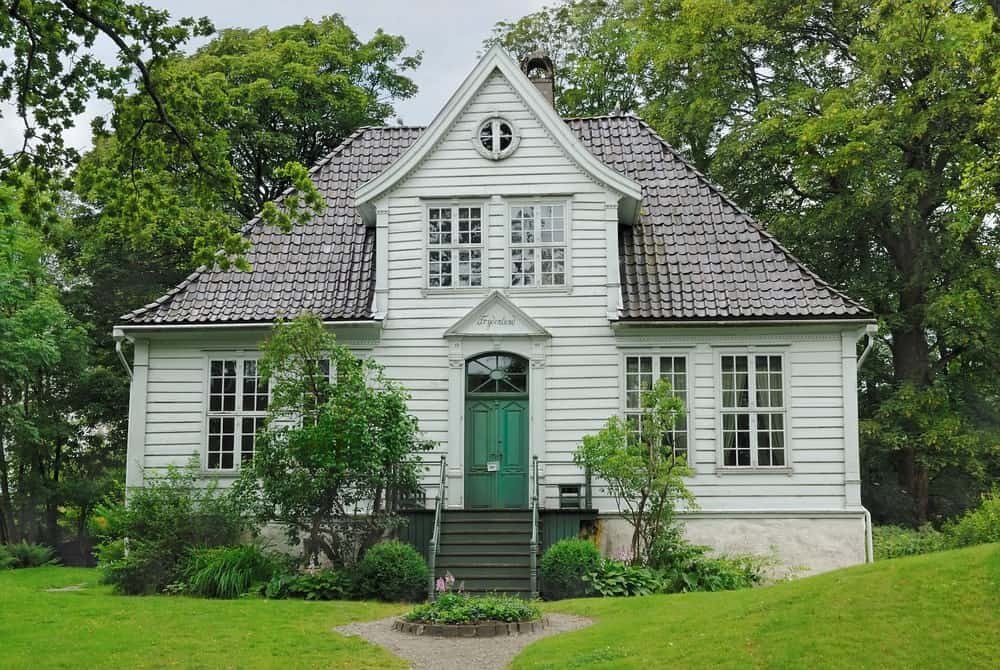 这种斯堪的纳维亚风格的景观完美地构成了这座简单的两层住宅。从两侧有树木和灌木的主门开始的台阶通向一个圆形的植物丘，这个植物丘在砾石人行道中间充当一个岛屿。