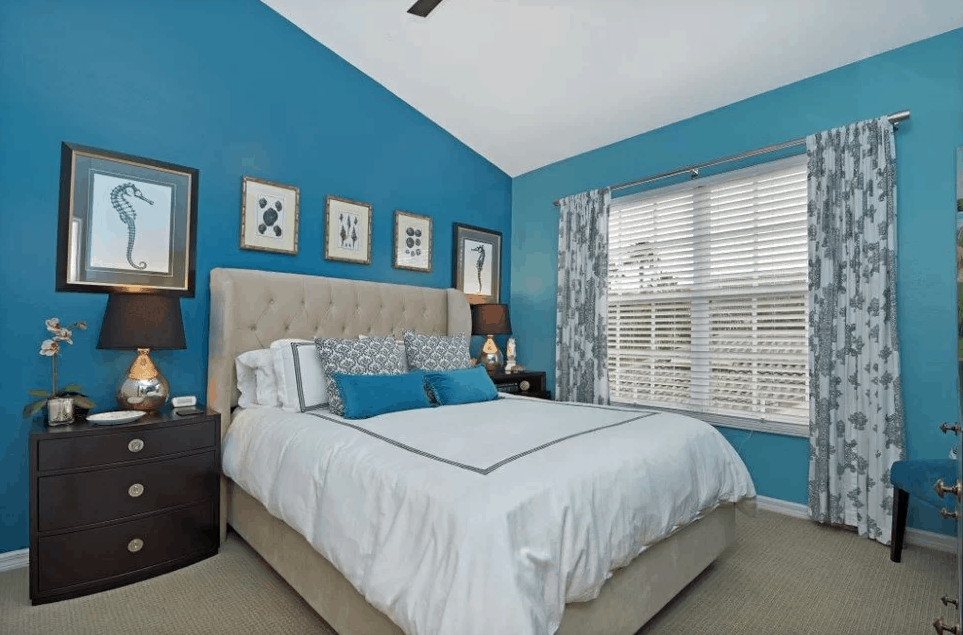 主卧室有地毯地板和蓝色的墙壁，以及一个高高的拱形天花板。