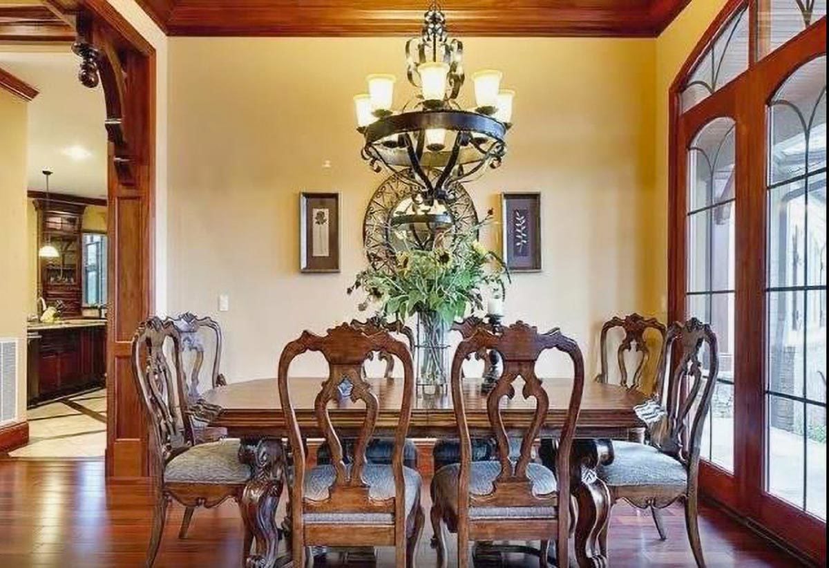 这个厨房散发着经典的氛围，它的锻铁吊灯，木制餐桌，以及与复杂细节相匹配的椅子。