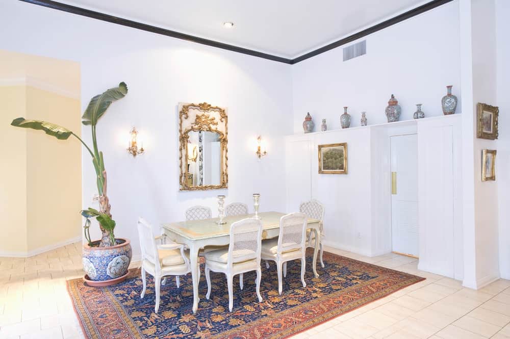 用餐区设有一个优雅的区域地毯，在那里餐桌和椅子的设置。空间被白色墙壁和白色瓷砖地板包围。
