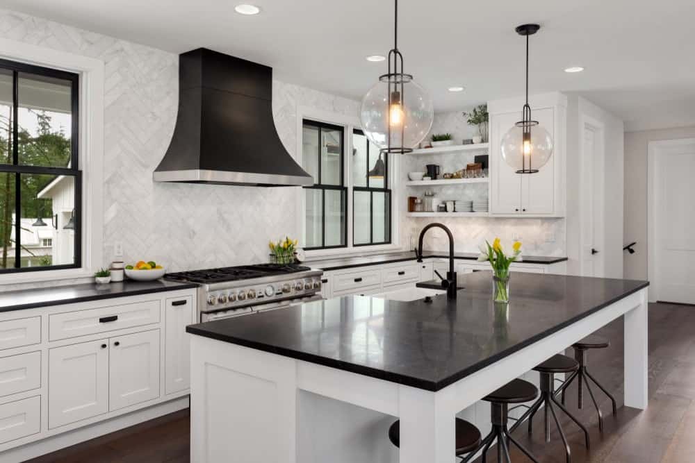 这个迷人而优雅的厨房有白色和黑色元素的微妙平衡，由硬木地板调解。厨房岛台和l形半岛的台面都是黑色的，与白色的橱柜形成对比。