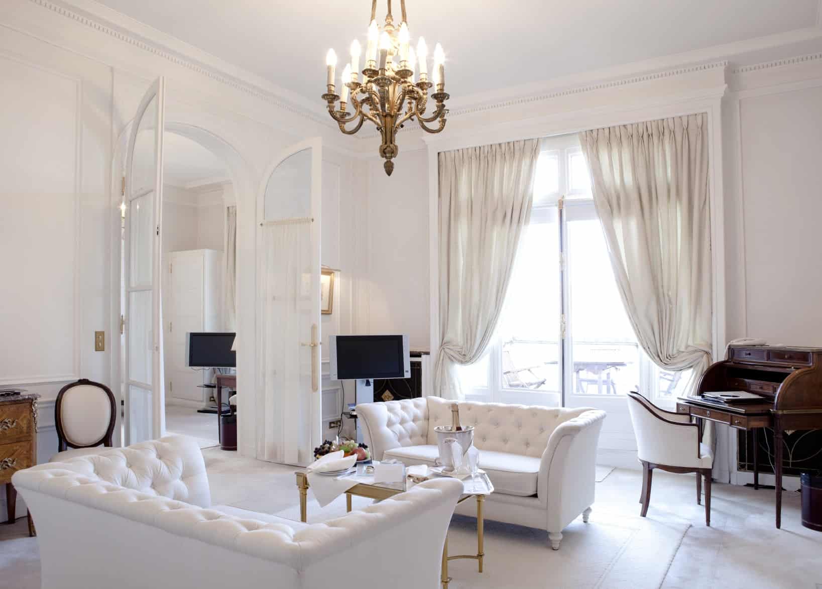 这间客厅的特色是白色的高档沙发和一张漂亮的中央桌子。房间里有一盏华丽的枝形吊灯。