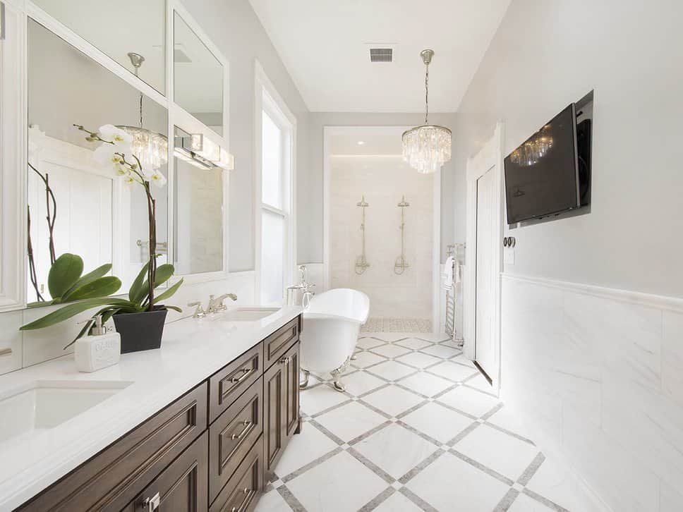 白色主浴室设有两个水槽和一个独立浴缸，以及开放式淋浴间和墙上的宽屏电视。