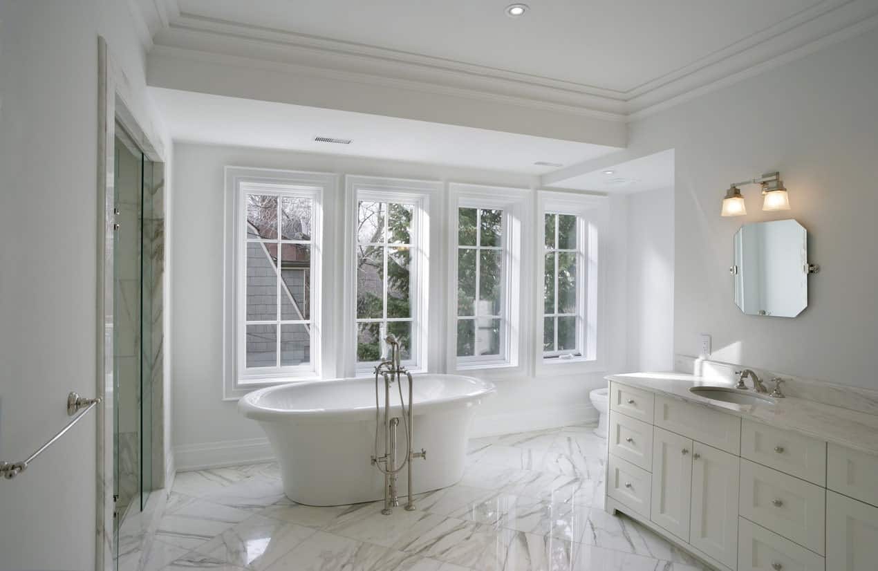 白色主浴室拥有美丽的大理石瓷砖地板。房内设有一座独立浴缸和一间步入式淋浴房。