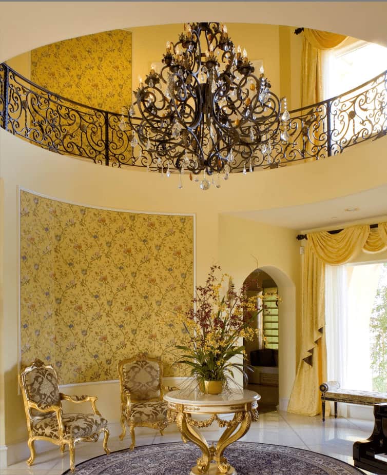 神话般的门厅被一盏花哨的吊灯照亮，并以迷人的花卉壁纸为重点。它有一张金色的中间桌子，配有配套的花纹扶手椅。