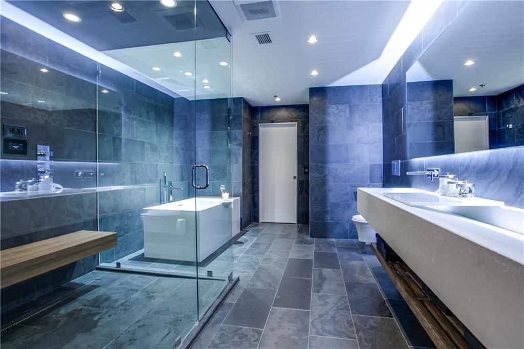 宽敞的主浴室拥有时尚的灰色地板和蓝色墙壁。它还提供一个独立浴缸、一间淋浴房和一个浮动洗手池。