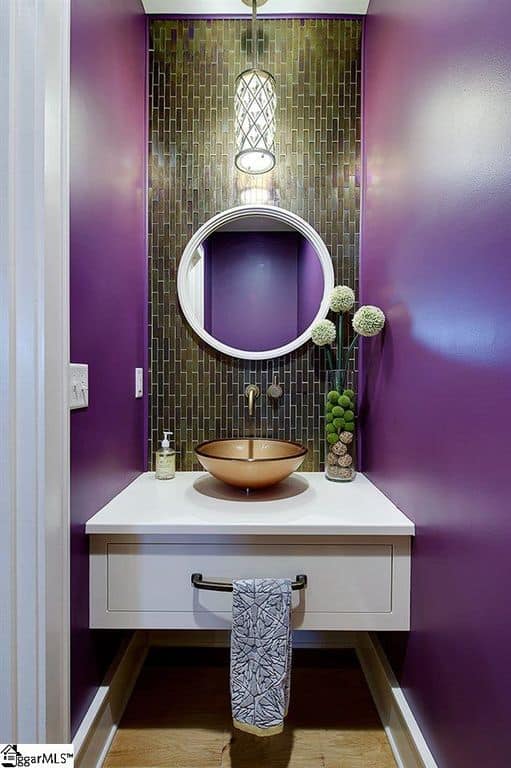 专注地看这个浴室的漂浮梳妆台，金色的水槽被紫色的墙壁包围着。