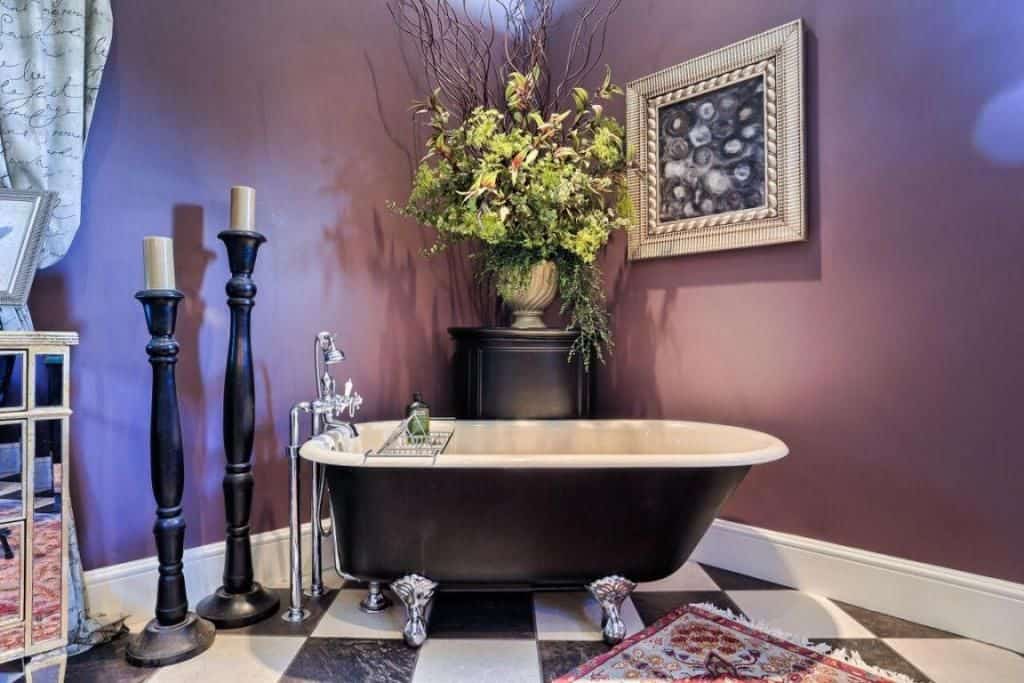 一个独立的浴缸设置在优雅的格子瓷砖地板上，周围是紫色的墙壁。