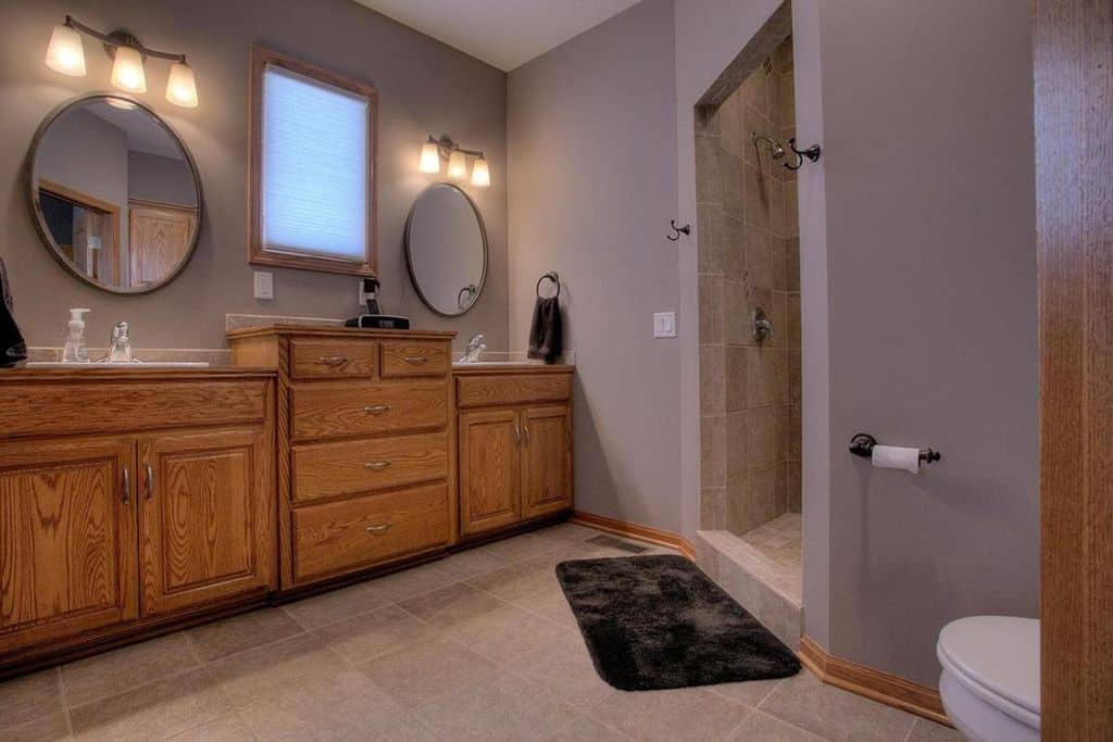 宽敞的主浴室设有紫色墙壁和两个水槽柜台，以及步入式淋浴房。这个房间靠壁灯照明。