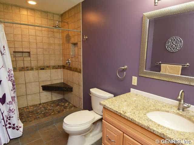主浴室设有花岗岩洗手台和开放式淋浴间，以及被紫色墙壁包围的厕所。