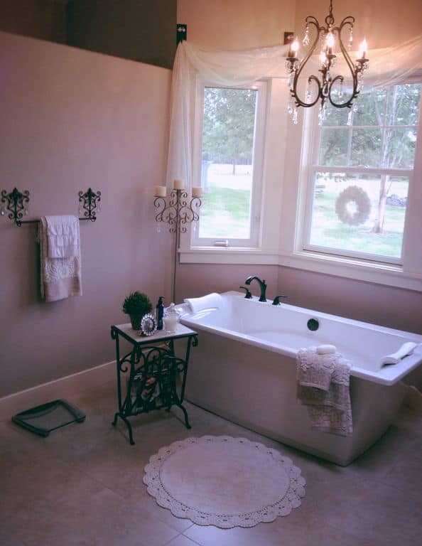 小浴室设有一个独立的浴缸设置在瓷砖地板上。房间四周是紫色的墙。