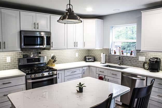 这间厨房设有白色摇床橱柜和抽屉，带有简单的银色把手，与现代厨房电器很好地搭配。