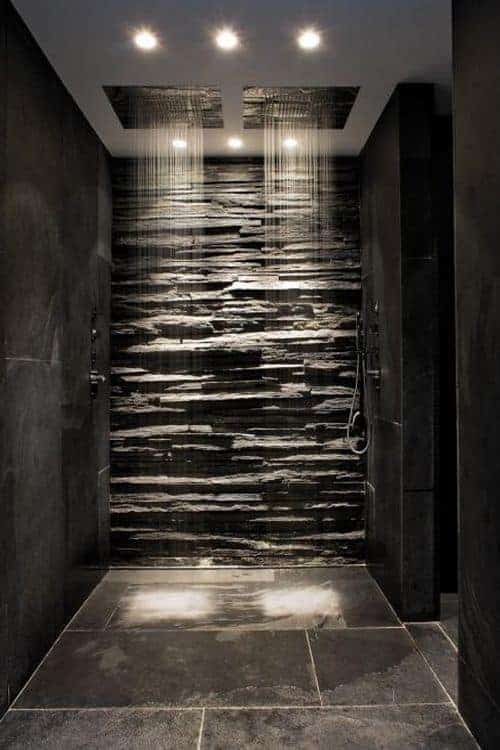 这个可爱的步入式淋浴区有一面有纹理的石墙，与黑色瓷砖墙形成对比，为头顶的淋浴房设置了一个漂亮的背景。