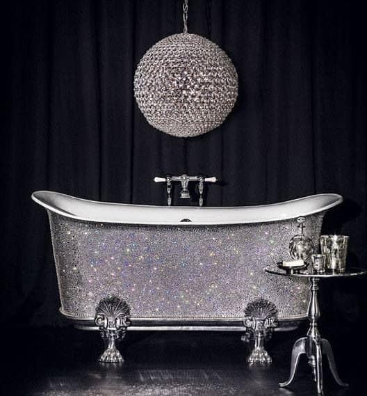 银色独立浴缸上方悬挂着一盏奇特的迪斯科球状吊灯，在黑色窗帘背景的映衬下闪闪发光。