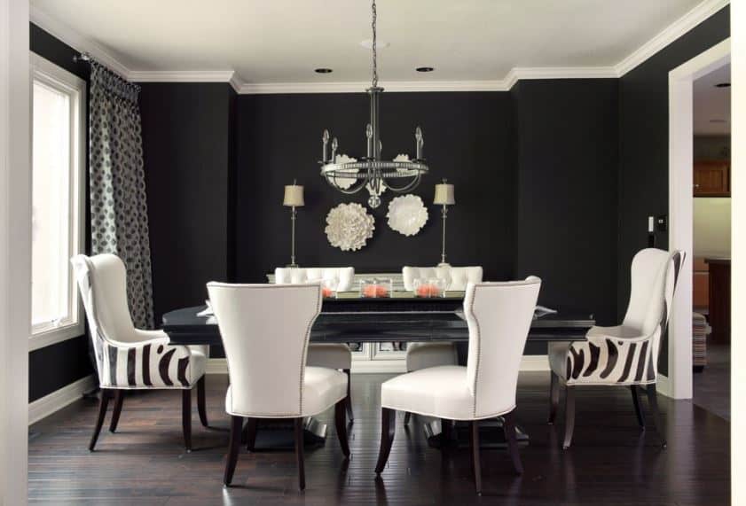 黑色的墙壁和黑色的木制餐桌与白色的皮革椅子形成对比，与白色的天花板相匹配。