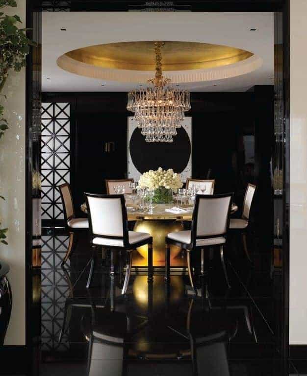 这个优雅的餐厅有一个白色的圆顶天花板和一个宏伟的水晶吊灯，在黑色的地板和墙壁上脱颖而出。