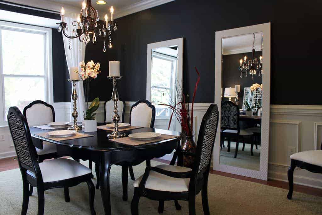 黑色木椅环绕着黑色木桌，与黑色墙壁和白色天花板上悬挂的吊灯相得益彰。