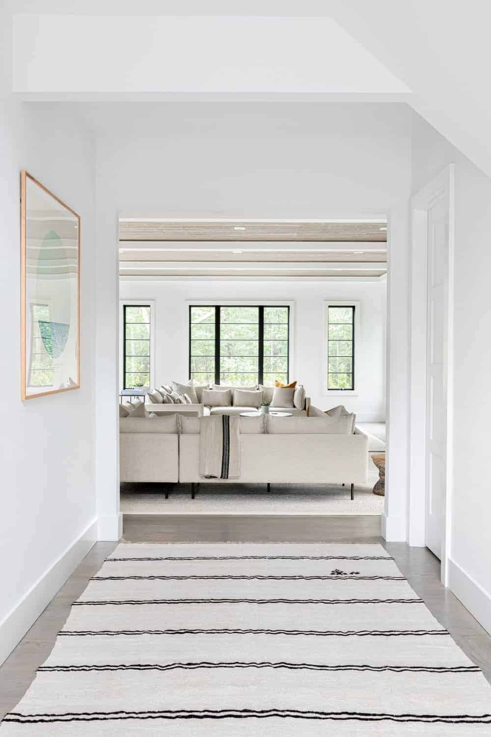 通往客厅的走廊，白色的墙壁和时尚的区域地毯。