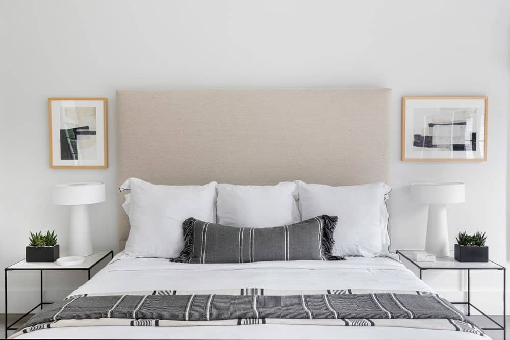 近距离观察主卧室的白色和灰色配色的现代大床，还有两个带台灯的边桌。