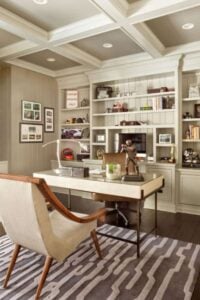 传统的家庭办公室的特点是灰色和白色纹理的地毯和固定在床头板墙上的内置搁架。