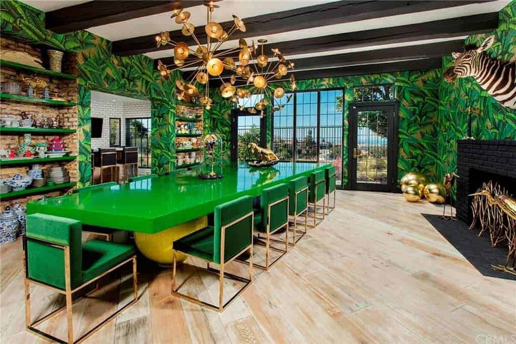 这是一个热带主题的餐厅，墙壁上装饰着树叶，与光滑的绿色餐桌相匹配。