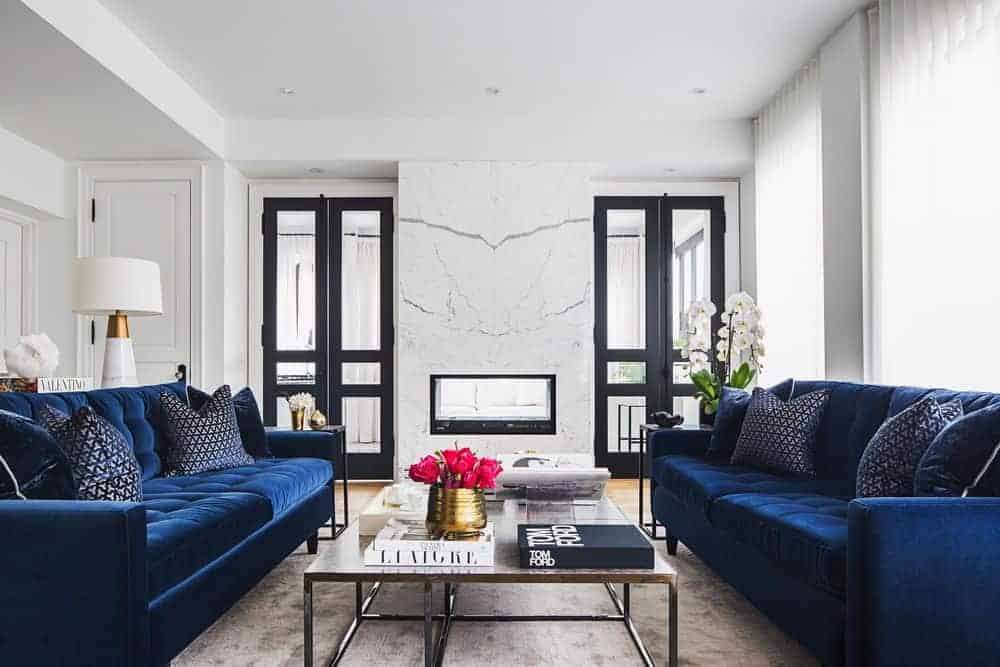 过渡风格的客厅，壁炉，蓝色沙发之间的咖啡桌，和一块小地毯。