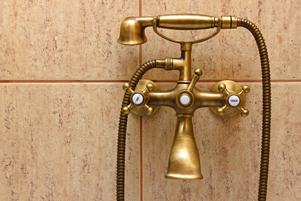 浴室的青铜水龙头安装在瓷砖墙上。
