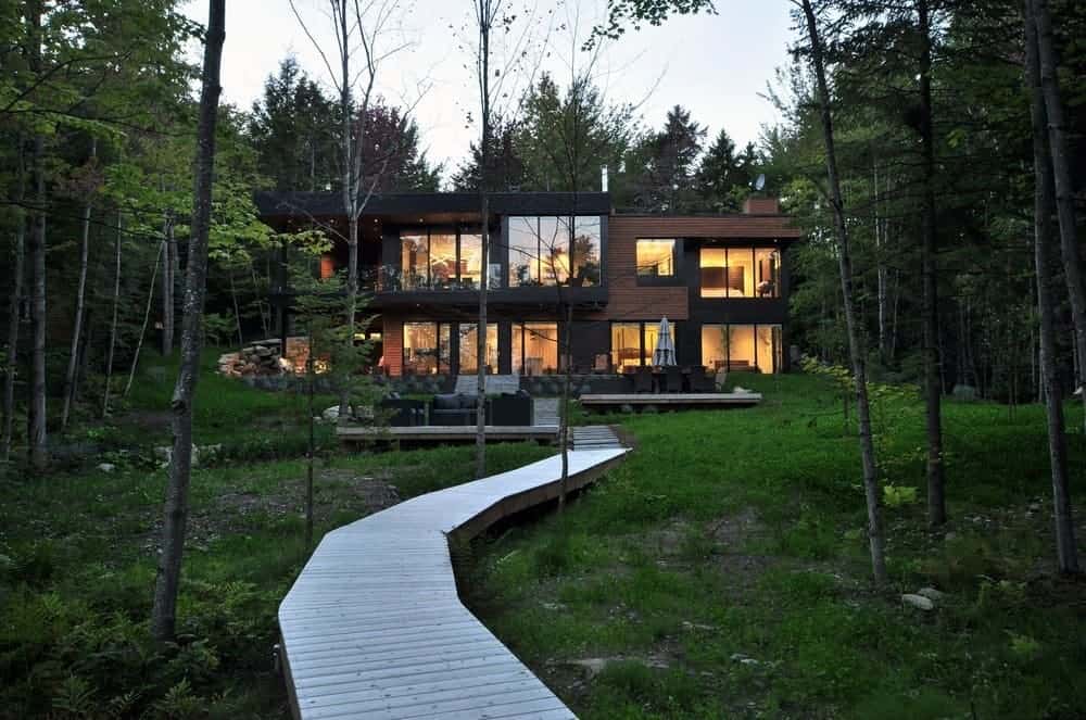 这座现代住宅位于森林中间，有一条漂亮的走道和一个清爽的户外区域。