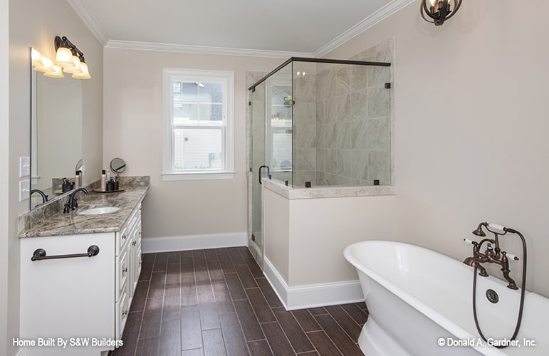 主浴室有一个花岗岩梳妆台，一个步入式淋浴间，和一个装有铜制固定装置的独立浴缸。硬木地板为米色的浴室增添了温暖。