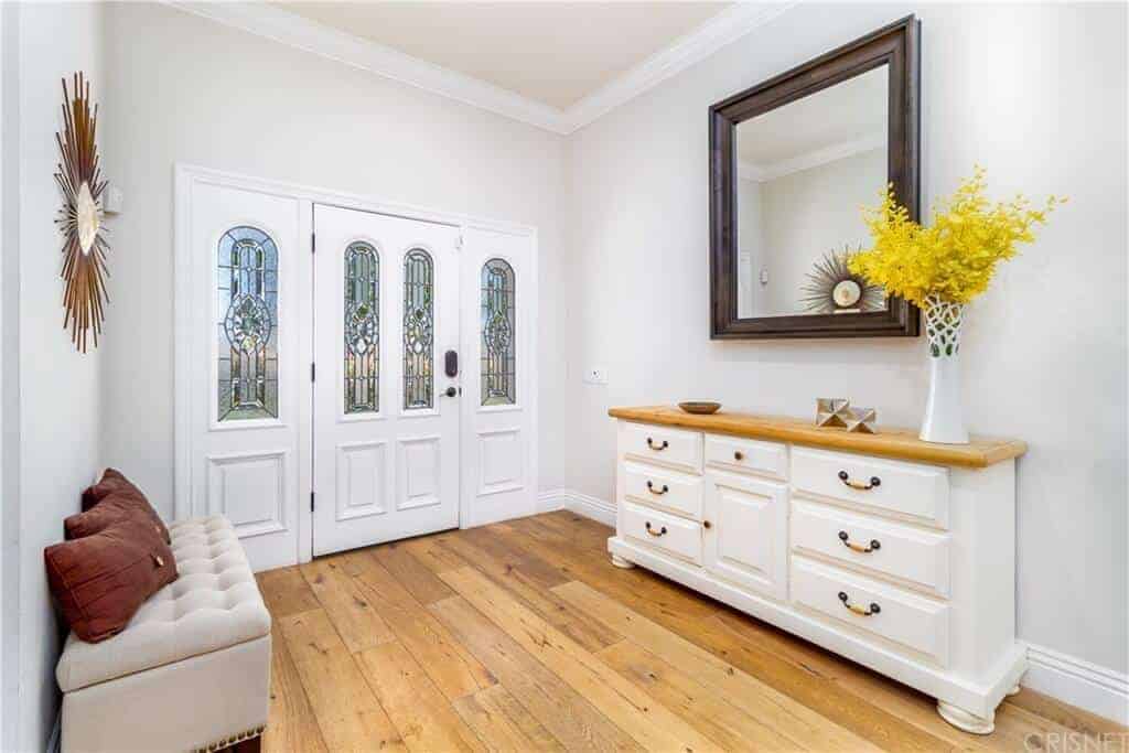 门厅的浅色硬木地板受到了热烈的欢迎，与一侧抽屉的木质顶部相匹配，抽屉也可以作为装饰者的控制台桌子和缓冲长椅对面的壁挂镜。