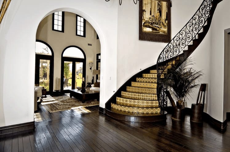 地中海式住宅，设有硬木地板和白墙的门厅，以及带有金色装饰台阶的楼梯。