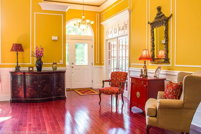 一个优雅的门厅，黄色的墙壁与白色的口音，以及红色的硬木地板。