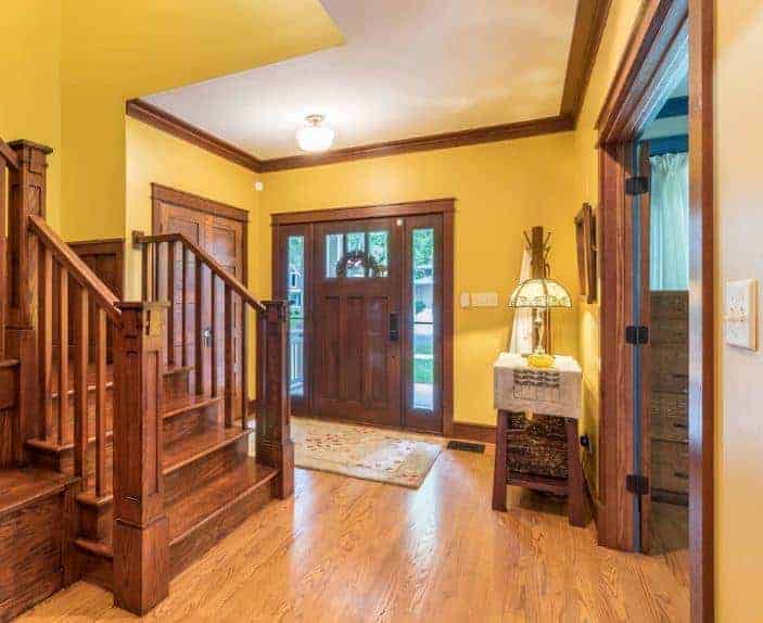 一个简单的门厅以黄色和棕色配色为特色。门和楼梯都是木制的。
