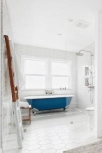 迷人的蓝色爪形浴缸和淋浴器有自己的私人区域，您可以在那里泡澡或淋浴。悬挂毛巾的两种色调的梯子和纹理地毯完成了这个宁静的海滩设计。