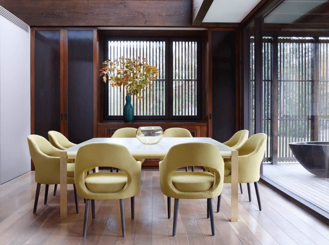 舒适的餐厅展示了黄色圆形靠背椅和木制餐桌，上面有一个玻璃碗。它包括内置的存储窗口与一个可爱的花瓶强调。
