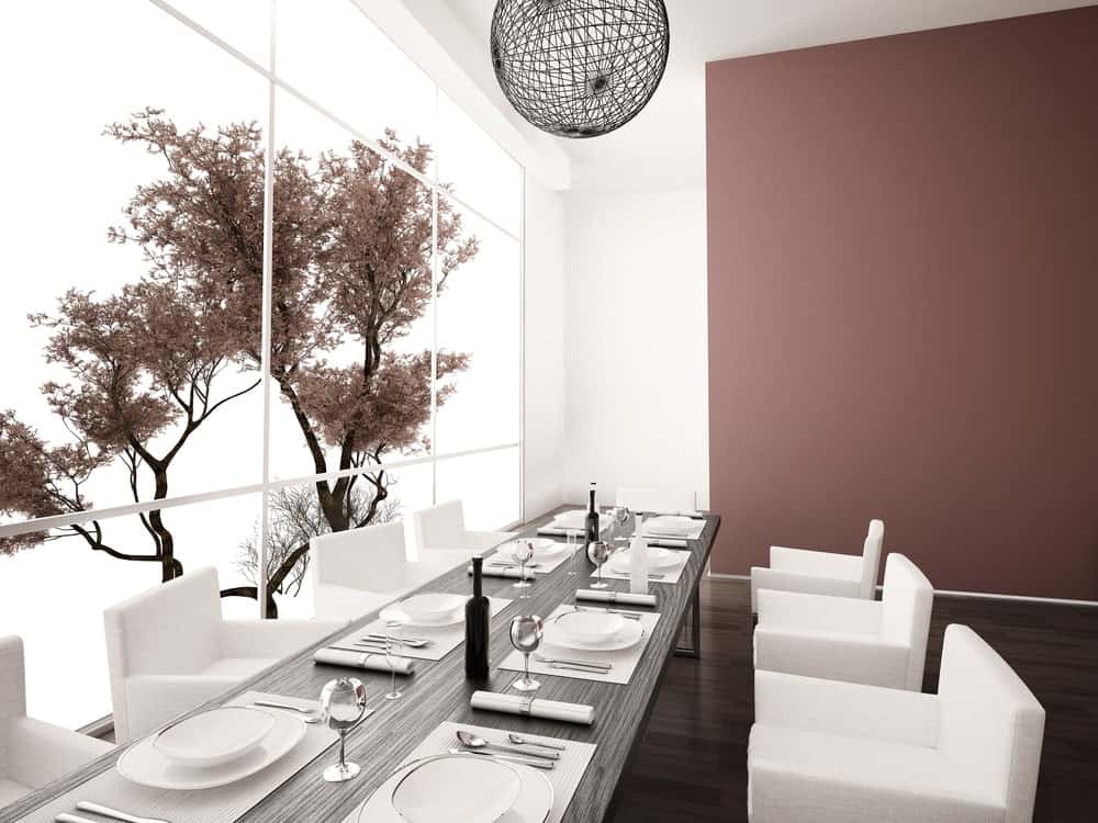 一个现代的亚洲餐厅，有光滑的白色椅子和木制餐桌，与硬木地板相辅相成，由编织的球形吊坠照亮。