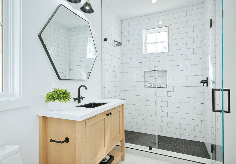 淋浴区的白色墙砖有砖墙图案，与木制梳妆台很相配。这个浴室的白色被小的黑色细节所强调，如水槽和水龙头，与浴室的其他黑色固定装置相匹配。