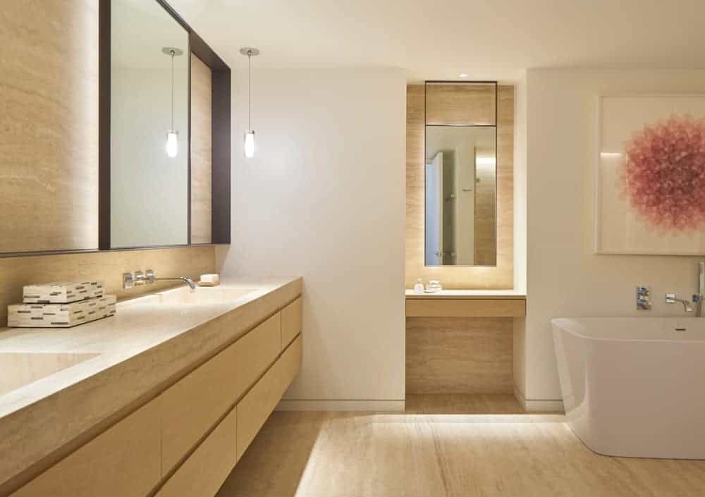 精致的主浴室配有双水槽梳妆台和独立浴缸，在光滑的硬木地板上，可爱的花卉墙壁艺术突出。