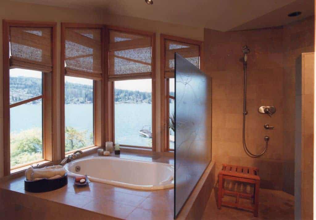这间浴室设有步入式淋浴间，设有木凳和浴缸，非常适合放松身心，透过覆盖着柳条罗马窗帘的玻璃板窗户，俯瞰令人惊叹的室外景色。