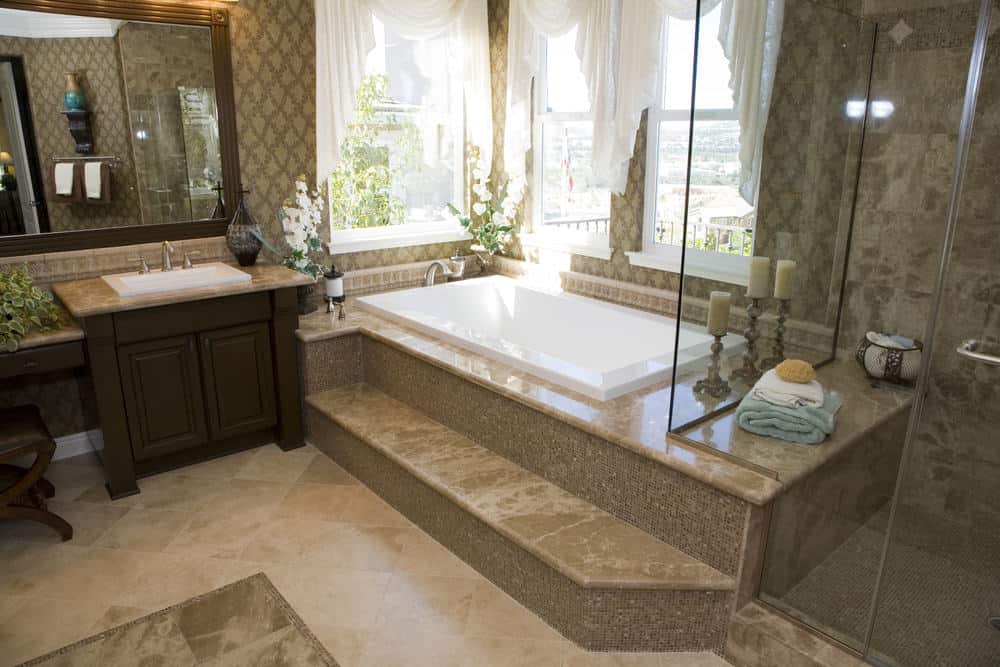 这张照片聚焦在主浴室的插入式浴缸上，浴缸的一侧有一个步入式淋浴区。房间装饰的棕色墙壁给房间增添了格调。
