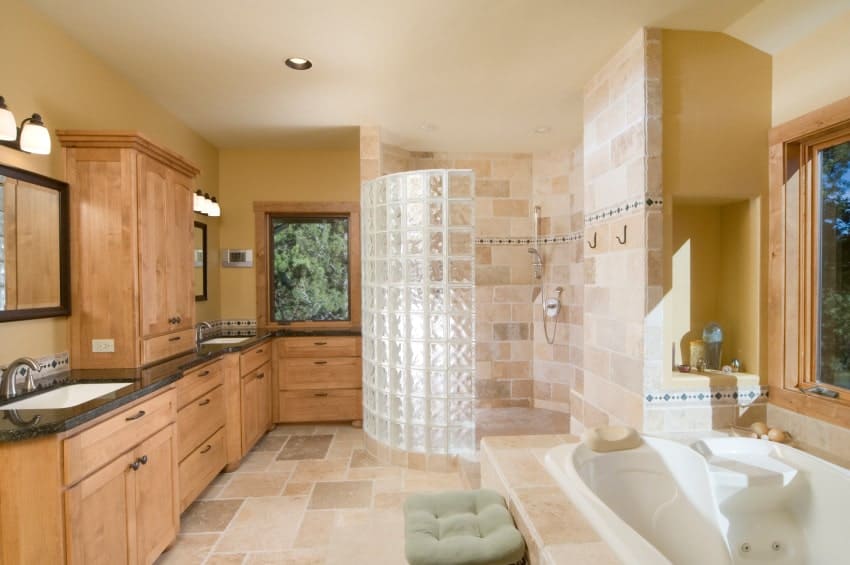棕色主浴室配有木制橱柜和花岗岩洗手台。房间里有一个插入式浴缸和一个步入式淋浴间。
