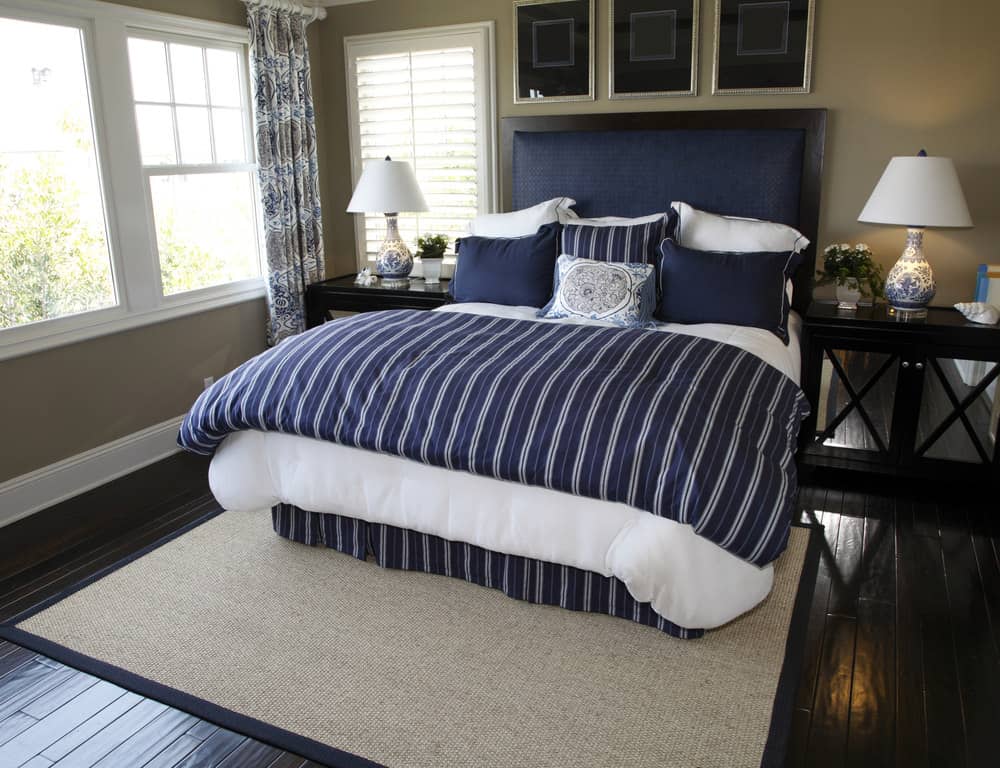 主卧室的藏青色床，硬木地板上铺着棕色地毯。