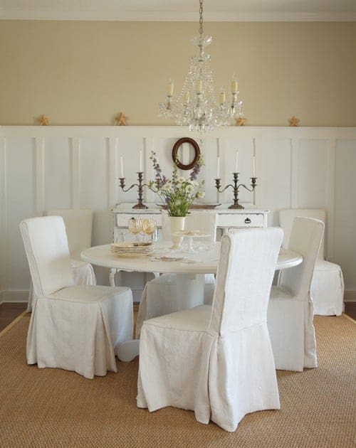 在这个精致的餐厅里，一盏水晶吊灯悬挂在白色的餐桌上，一张黄麻地毯和一张破旧的控制台桌子靠在床头板下的墙上。