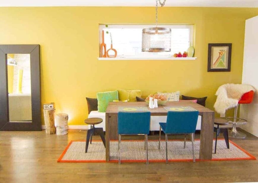 不拘一格的餐厅，黄色的墙壁和硬木地板。它有一张带沙发的木制餐桌。