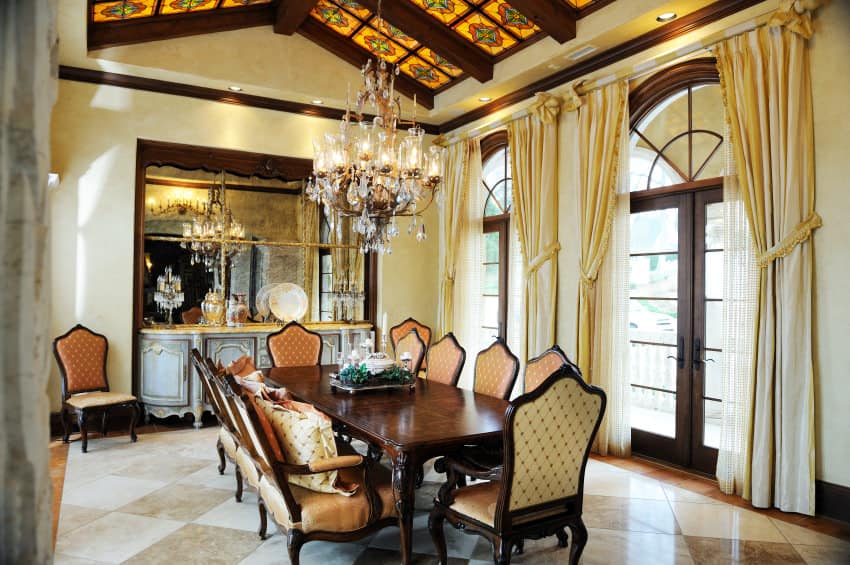 不拘一格的餐厅，优雅的餐桌和椅子，由一个优雅的吊灯悬挂在高高的装饰拱形天花板上。